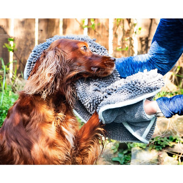 A brown dog being dried down with the Henry Wag Noodle Glove towel in a garden setting.