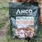 Dog sitting next to a bag of ANCO Naturals Chicken 'n Chips treats.
