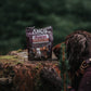 Dog looking at a packet of Anco Trainers Chicken treats on a tree stump.