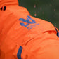 Lifestyle image of the Orange Fjord Overall, with Non-stop branding and rain falling on the coat.