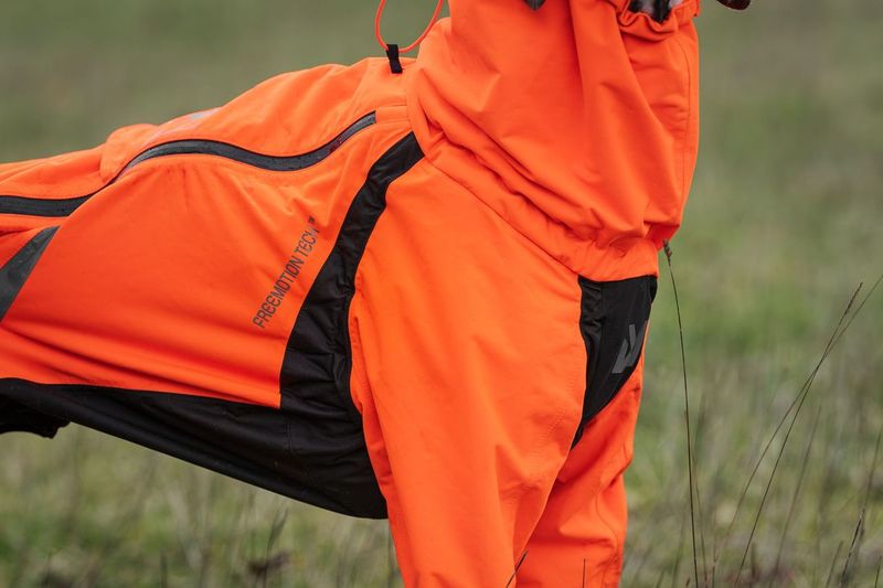 Lifestyle image of the Orange Fjord Overall, showing the shape of the coat against a grassy environment.