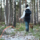 Lifestyle image of the Friction Long Line, with a lady holding the length and a dog ahead of her, in a woodland environment.
