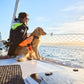 Lifestyle image of the Protector Life Jacket, showing a dog sitting on the end of a boat with a person, looking out into the ocean.