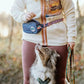 Lifestyle image of the Rachel Pohl Trail Quest Storage Pack, with a dog between the legs of their owner, waiting for a treat.