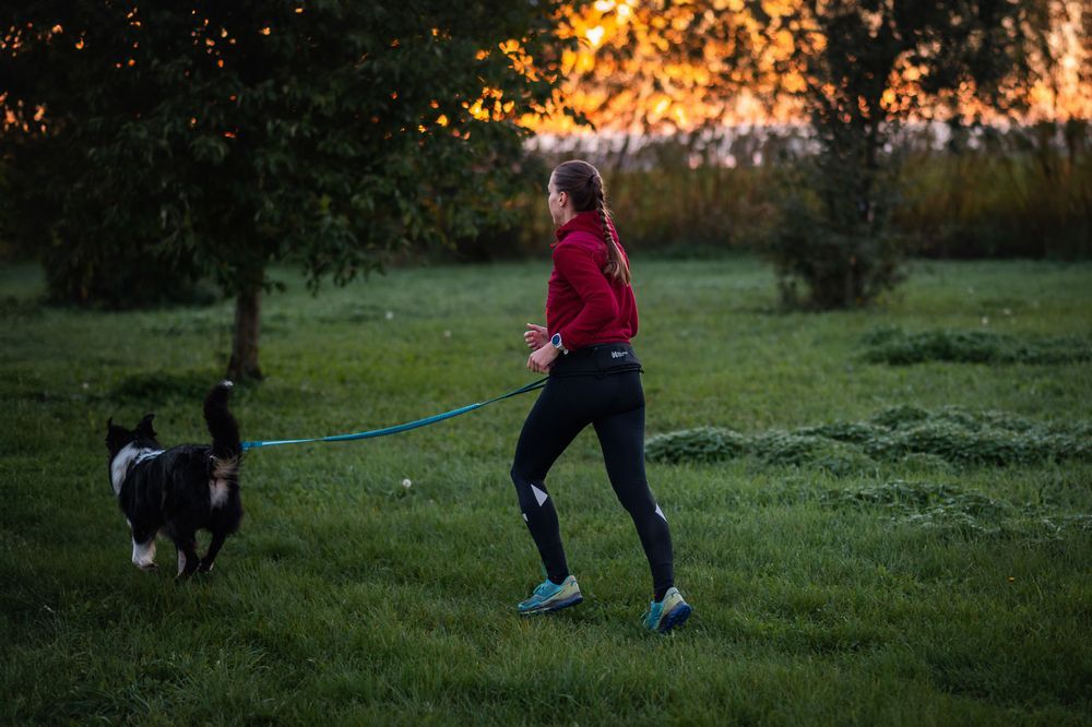 Lifestyle image of the Rush Belt, showing the belt being worn by a lady as she runs with her dog.