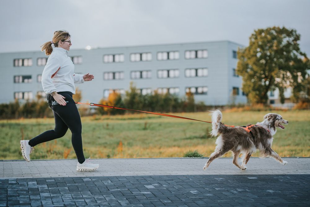 Lifestyle image of the Rush Harness, being worn by a lady running in front of a building.