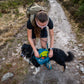Woman hiking with a dog on a trail, filling the dog's Trail Quest Backpack.