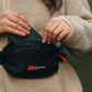 A woman placing her phone into the Trail Quest Storage Pack, with a sherpa jacket on.