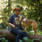 Lifestyle image of the Crag EX Lead. worn by a brown and white dog. The dog and their owner are sat on a log bonding, with a forest background.