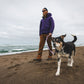 Lifestyle image of the Front Range Collar being worn at a beach, with a person and dog walking in front of the sea.