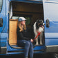 Lifestyle image of the Front Range Harness, with an owner sat beside a dog in a campervan, holding a lead.
