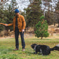 Lifestyle image of the Gnawt-a-Stick being held above a dog, in a forest environment.