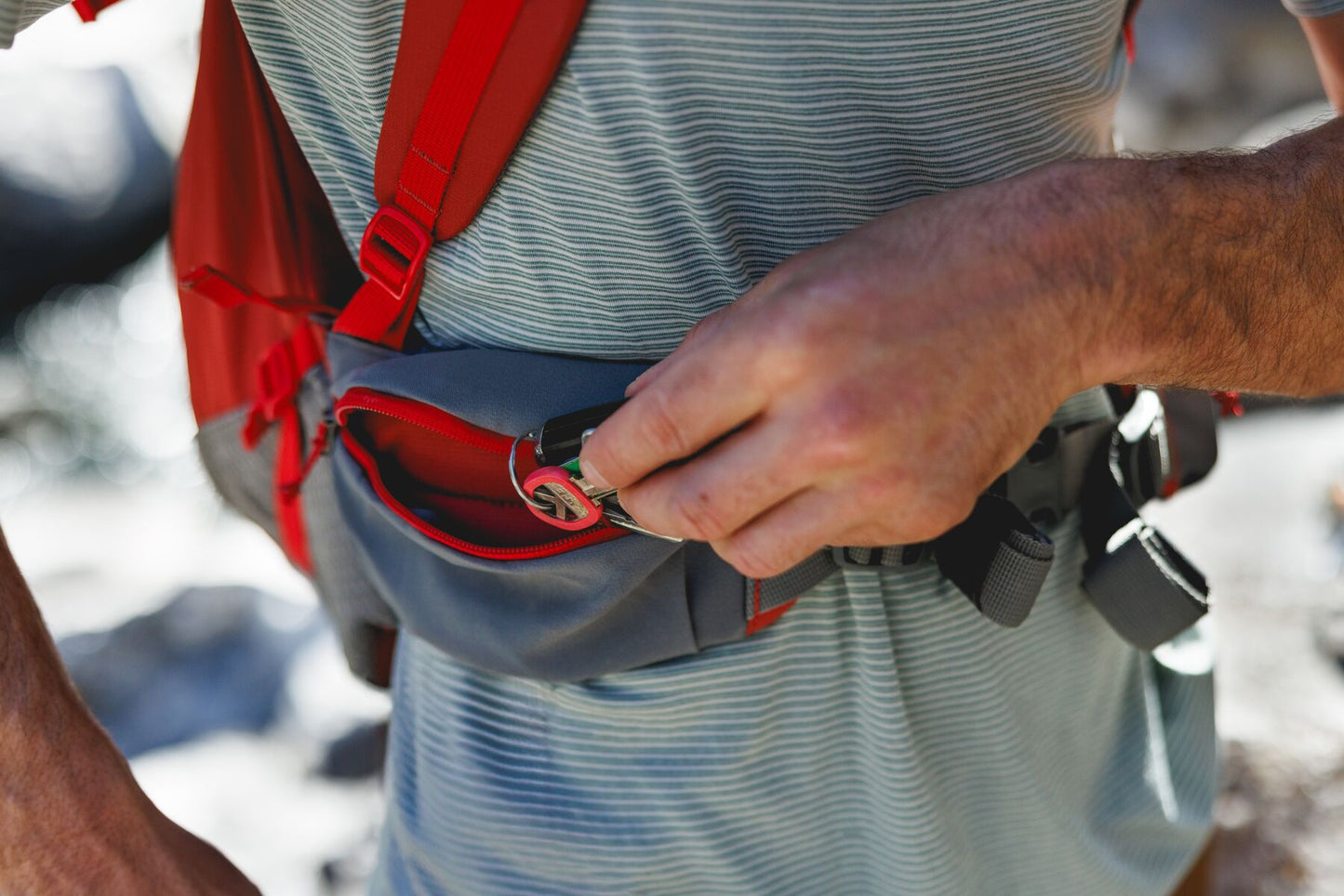 Lifestyle image of the Hitch Hiker Carrier, showing a hand placing keys into the compartment of the bag.