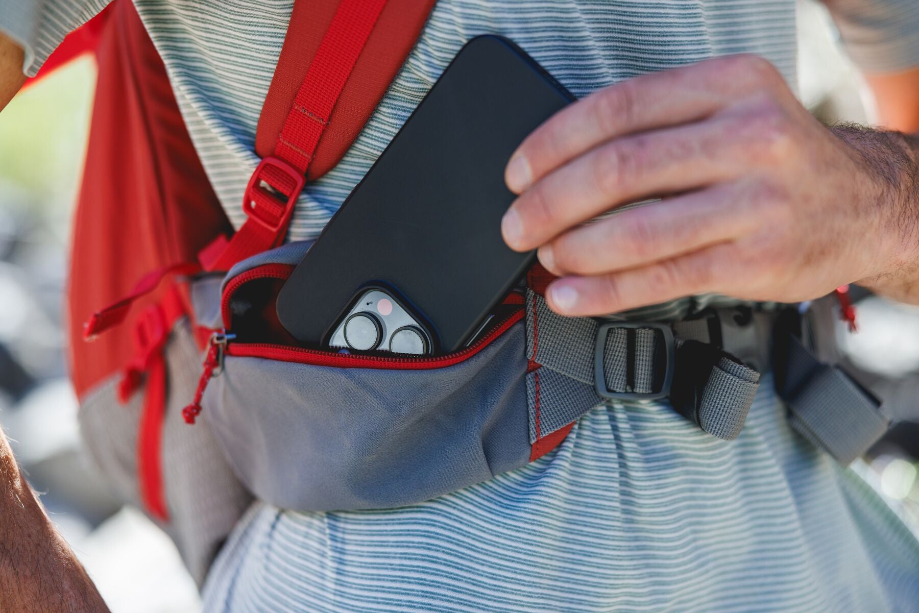 Lifestyle image of the Hitch Hiker Carrier, showing a phone being put into the compartment.