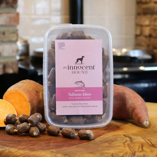 The Innocent Hound Salmon Bites Treats are displayed on a wooden surface with treats and ingredients.