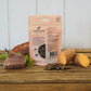 The back of the Innocent Hound Training Crab and Tuna Treats packets are displayed on a wooden surface with treats and ingredients.
