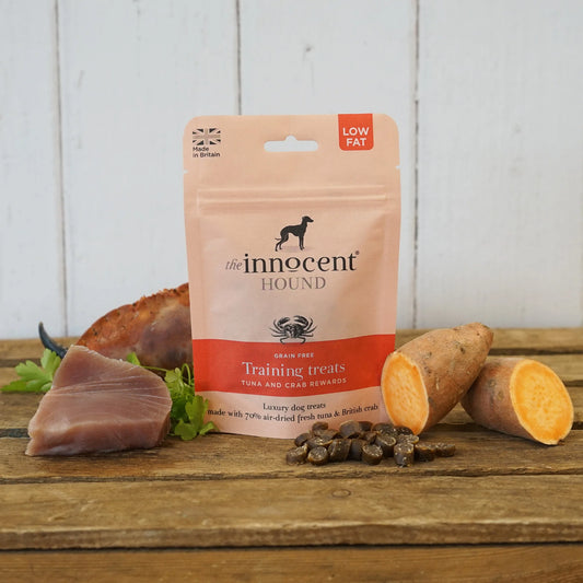 The Innocent Hound Training Crab and Tuna Treats are displayed on a wooden surface with treats and ingredients.