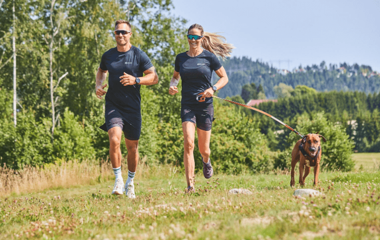 Lifestyle image of the Move Lead, with two people running alongside a brown dog.
