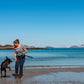 Lifestyle image of the Strong Lead, with a brown dog and their owner stood in front of the ocean.