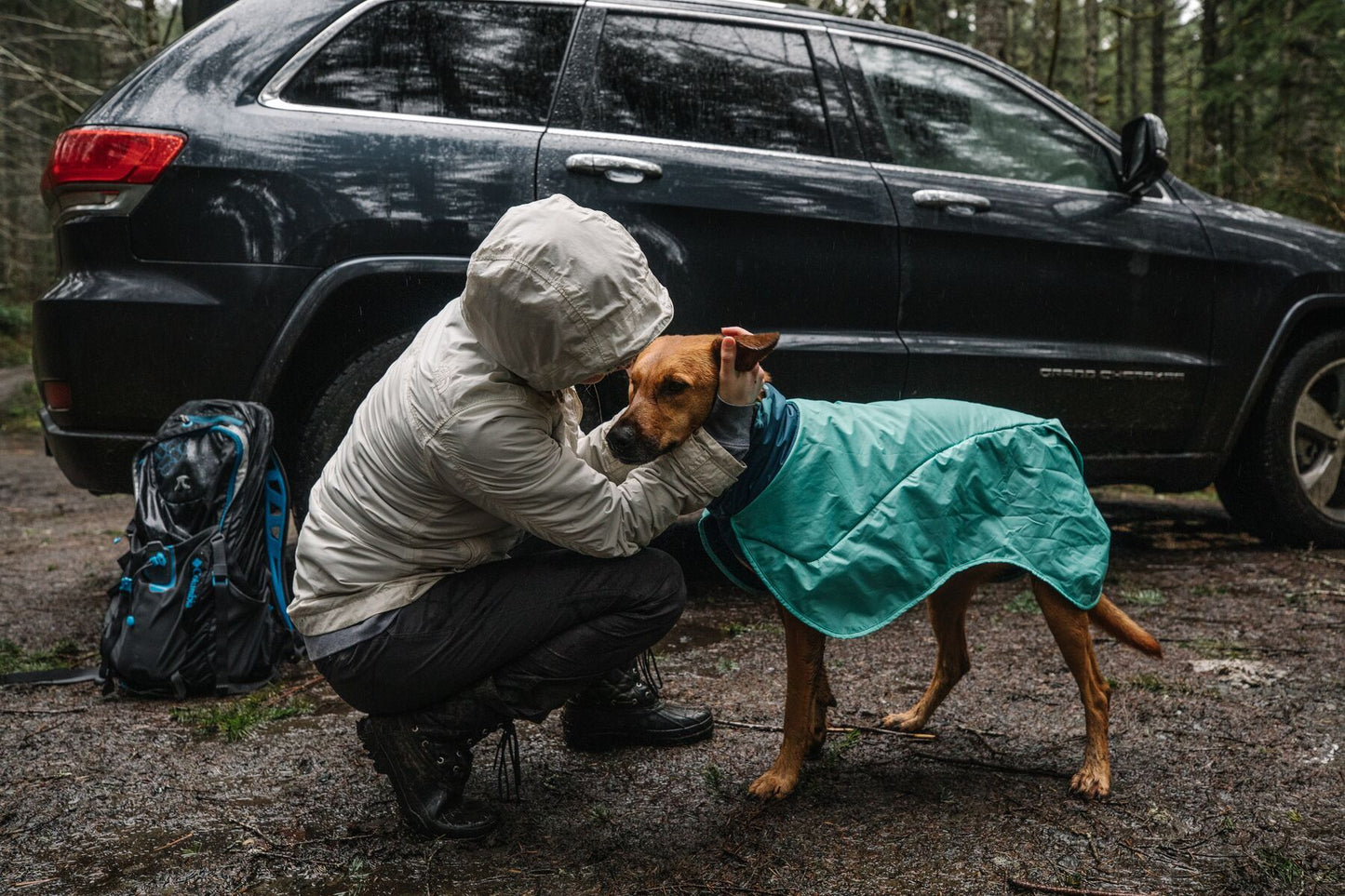 Dog, wearing a Dirtbag Dog Towel, gets a cuddle beside a car.