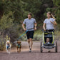 Two dogs being walked by their owners, using the Double Track Coupler to walk them together.