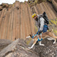 Dog and their owner traversing some rough terrain. The hiker holds onto the dog's harness handle for stability.